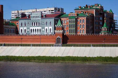 The promenade along the waterfront with views of stone buildings and a brick wall with a towerの写真素材