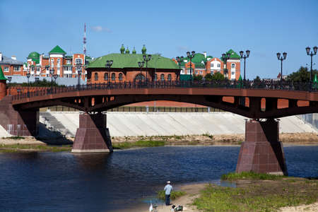 The bridge on the river overlooking the houses and the concrete wall of the promenadeの写真素材