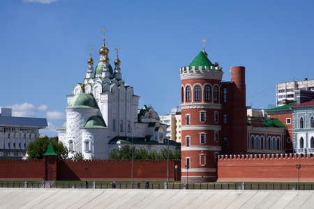 white Orthodox Church with a tower and a wall of red brick on the waterfront