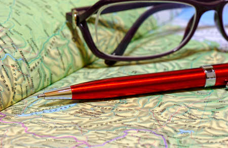 Ballpoint pen and glasses lie on geographical atlasの写真素材