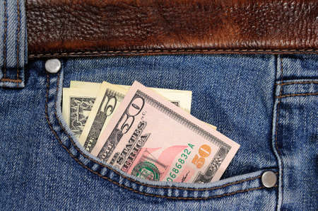 Several dollars banknotes seen from the pocket of jeans