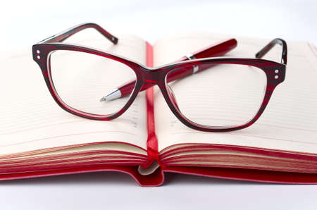 Red Daily planner with eyeglasses and pen, closeupの写真素材