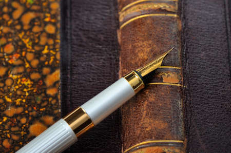 Fountain pen with a gold pen lying on old book, closeup, shallow DOFの写真素材