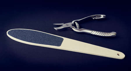 Metal nippers for nails and grater for heels on dark background