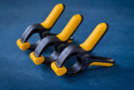 Three plastic spring clips on blue background, closeup, shallow depth of fieldの写真素材