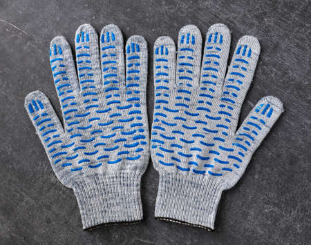 Cotton gloves with blue rubber studs on gray background