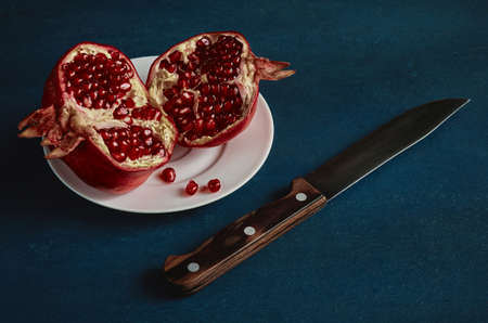 Ripe fruit pomegranate and knife on dark background, vintage stylizationの写真素材