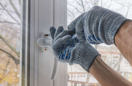 Worker mounts the handle to the window frame made of plastic. Creating comfort and coziness in your home, close upの写真素材
