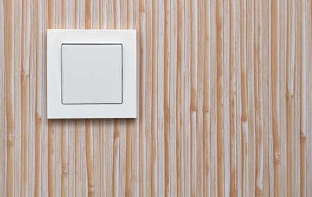 White electric light switch on the background of plastic wall panels. Home electricity.