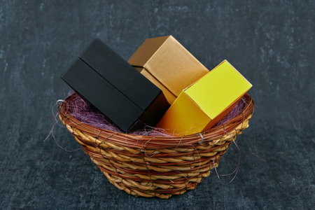 Three gift boxes of different colors in a wicker basket