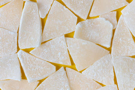 Slices of dried coconut on a yellow background, close upの写真素材