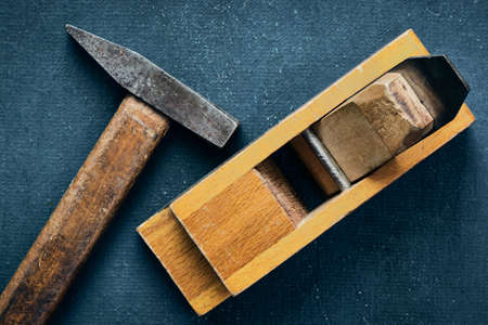 Carpenter tools, old hammer and hand planer on blue background