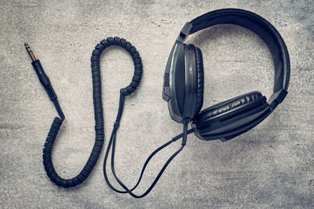 Black studio retro headphones on gray background, professional earphones, tinted