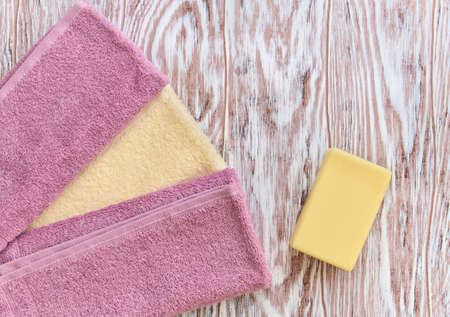 Piece of toilet soap and towel on a wooden background