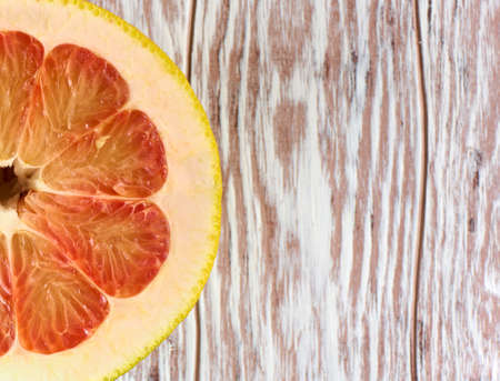 Red grapefruit half on a wooden background with copy space