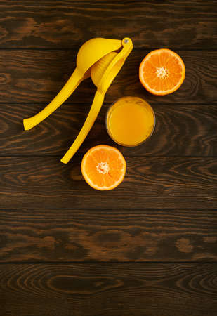 A glass of juice, ripe tangerine and a hand juicer on a wooden tableの写真素材