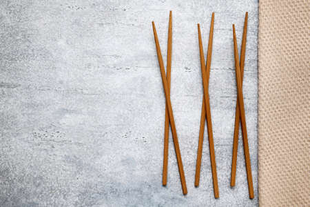 Collection of dark wooden bamboo food sticks and cotton napkin on a gray background with copy spaceの写真素材