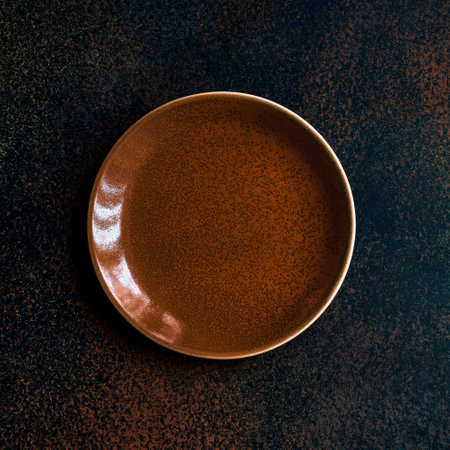 Empty ginger color plate on dark background. Top view, with copy spaceの写真素材