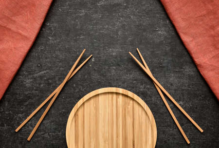 Rolls sticks and an empty plate of bamboo on a gray background with space for textの写真素材