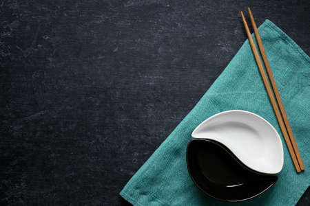 Yin-yang bowls and chopsticks on green linen napkin, dark gray background with copy spaceの写真素材