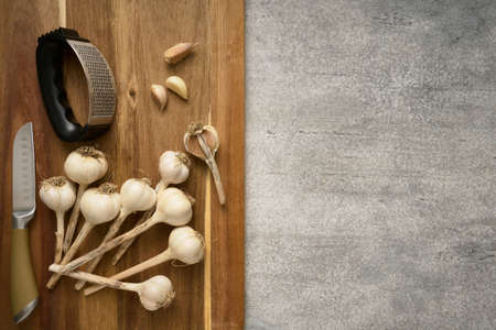 Wooden cutting board with garlic heads and garlic press, close upの写真素材