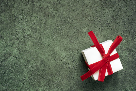 White gift box with red velvet bow in close-up, copy space, shallow depth of field