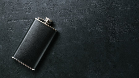Pocket steel flask in leather trim for travel on the dark background with copy space, tanks for cognac, whiskey, rum and various alcoholの写真素材