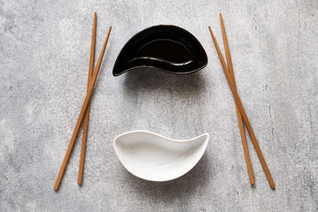 Ceramic Yin-Yang bowls and wooden bamboo chopsticks lie on the betton tableの写真素材