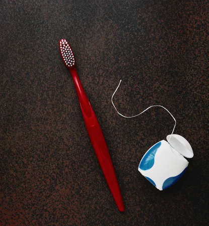 Toothbrushe and dental floss on dark background close up, with copy space