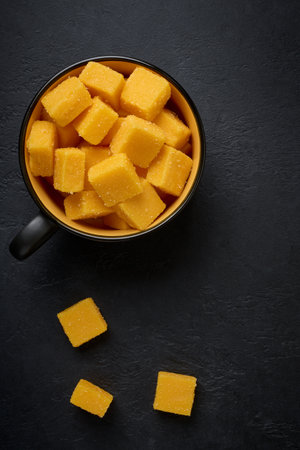 Cubes of sweet ripe mango in sugar in a cup on a dark backgroundの写真素材