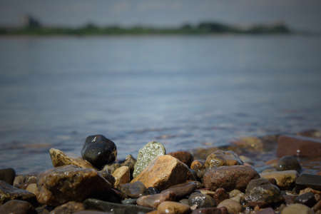 Pebble stones on the shore close up in the blurry distance background. Natural backgroundの写真素材