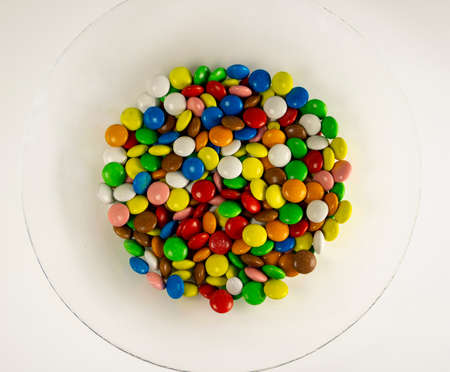 A plate of multicolored jelly beans on a white background. The decoration of the background. Close...