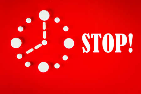 Clock made of white tablets with inscription STOP , on red background, top view. 2019 Novel Coronavirus 2019-nCoV concept.の写真素材