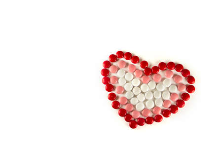 Colorful dragee beans in the shape of a heart on a white background. Decoration background. Closeup.