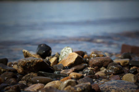 Pebble stones on the shore close up in the blurry distance background. Natural background. Selective...