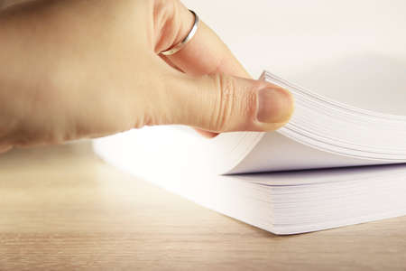 Stack of paper on office desk for report papers . Close up of stack paper. Females hand touching paper, close up view.の写真素材