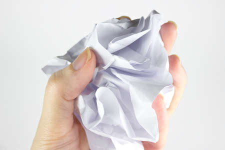 A woman's hand holds a crumpled paper ball with a copy of space on a gray background. Crumpled paper in hand, hand and crumpled paper, on a white backgroundの写真素材