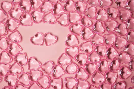 Valentines Day Concept. Two red hearts in an environment glass transparent hearts on pink background, glass heart glows, glass painting. Many red glass hearts. Love for Valentine's day. Copy space.の写真素材