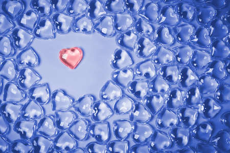 Valentines Day Concept. One red heart in an environment glass transparent hearts on pink background,...