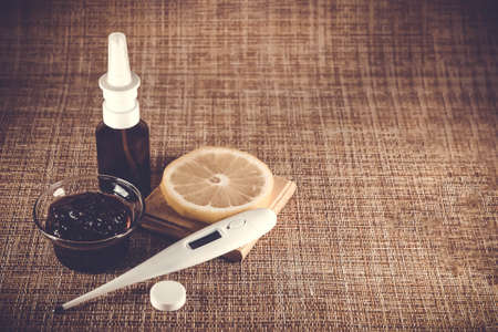 Treatment of colds and flu. Various medications, thermometer, cold pills, throat spray, nasal drops, lemon on a brown background. Treatment of influenza. Copy space.Medicine flat layの写真素材