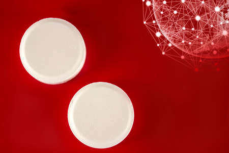 White medication pills lie with virtual hologram earth on a red background. Medicine, pharmacy and healthcare. Empty space for textの写真素材