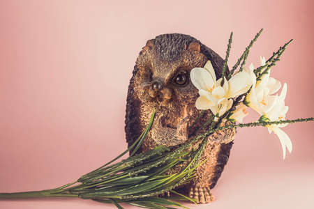 Happy smiling decorative ceramic figurines hedgehog with flowers on a pink background.の写真素材