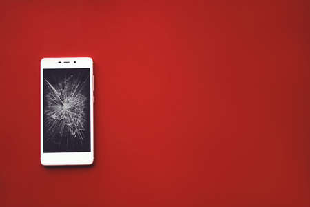 Mockup image of white mobile phone with broken black screen on red backgroundの写真素材