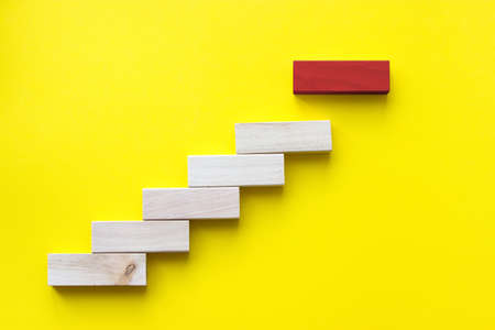 Red wooden block on yellow. Business planning, Risk Management, Solution, leader, strategy, different and Unique Concepts. Wood block stacking as step stair. Concept for business growth success process, Copy spaceの写真素材