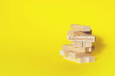September 28th. Day 28 of month, Calendar date. Wooden blocks folded into the tower with month and day on yellow background, with copy space. Autumn month, day of the year conceptの写真素材
