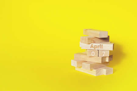 April 7th. Day 7 of month, Calendar date. Wooden blocks folded into the tower with month and day on yellow background, with copy space. Spring month, day of the year conceptの写真素材