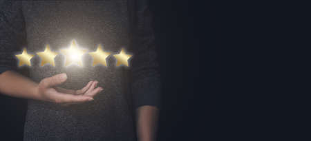 Five Star Rating. Hand holds the fifth star. Quality level, good serviceの写真素材
