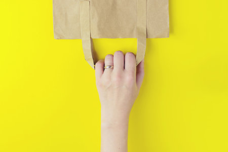 shopping paper bag on the yellow background with copy space. flat lay photo of upturned bagの写真素材