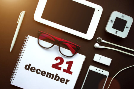 December 21st. Day 21 of month, Calendar date. Office workplace with laptop, notebook, office supplies and stationery on brown back. Winter month, day of the year conceptの写真素材
