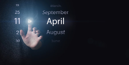 April 11st. Day 11 of month, Calendar date. Hand click luminous icon PLAY and DATE on dark blue background. Spring month, day of the year conceptの写真素材